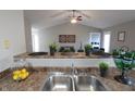 Open kitchen with granite countertops, stainless steel sink, and view into the living area at 11598 Wilderness Trl, Fishers, IN 46038