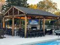 Covered outdoor kitchen with a fireplace, bar seating, and a view of the pool at 1258 Soaring Eagle Dr, Greenwood, IN 46143