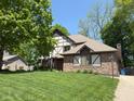 Two-story home featuring Tudor accents, brick facade, an American flag, and green lawn at 1728 Timber Heights Dr, Carmel, IN 46280