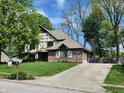 Traditional Tudor-style home featuring a brick facade, attached garage, and green front lawn at 1728 Timber Heights Dr, Carmel, IN 46280