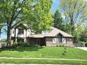 Beautiful Tudor-style home with green lawn and mature trees with a well manicured lawn at 1728 Timber Heights Dr, Carmel, IN 46280