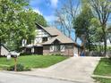 Lovely Tudor-style home with a long driveway, chimney and attached garage with a freshly cut lawn at 1728 Timber Heights Dr, Carmel, IN 46280
