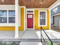 Inviting covered front porch with yellow siding, white trim, and a vibrant red front door at 251 Hendricks Pl, Indianapolis, IN 46201