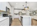 Open kitchen features an island with stainless steel appliances, white countertops and cabinets, and modern pendant lights at 2777 Penn Ave, Plainfield, IN 46168