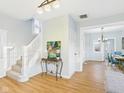 Inviting entryway featuring hardwood floors, a staircase with white railings, and a glimpse into the brightly lit dining room at 411 W Memorial Dr, Muncie, IN 47302