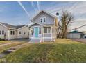 A cozy two-story house with gray siding, a quaint front porch, and a well-maintained lawn, perfect for a starter home at 411 W Memorial Dr, Muncie, IN 47302