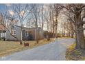 Inviting home with a gravel driveway, mature trees, and a glimpse of a gazebo in the background at 426 Della Rd, Columbus, IN 47203
