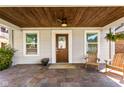 Inviting front porch featuring wood ceiling, stone floor, seating and wood door with glass at 4707 N Park Ave, Indianapolis, IN 46205