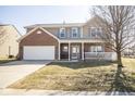 Charming two-story home featuring a brick front, attached garage, and inviting front porch at 5897 W River Chase Ln, McCordsville, IN 46055
