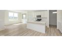Bright, white kitchen with island, modern appliances, and wood-look flooring, bathed in natural light at 6848 Jacone Dr, Brownsburg, IN 46112