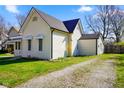 Side view of a cozy home with light siding and gravel driveway, complemented by a green lawn at 93 Walnut St, Indianapolis, IN 46227