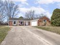 A view of a brick home showcasing an attached garage and driveway, with a well-maintained front lawn at 1840 Hibiscus Dr, Indianapolis, IN 46219