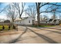 Street view of the home with gravel driveway, small fence and mature trees at 3225 S Rybolt Ave, Indianapolis, IN 46221