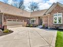 Paver driveway leading to a brick home with a two-car attached garage and manicured landscaping at 3559 Towne Dr, Carmel, IN 46032