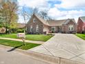 Charming brick home on a large lot featuring mature trees, lush lawn and a patterned concrete driveway at 3559 Towne Dr, Carmel, IN 46032