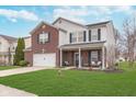 Inviting two-story home featuring a cozy front porch, brick detailing, and a green front yard at 8335 S Shady Trail Dr, Pendleton, IN 46064