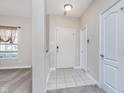 Welcoming foyer with neutral tile flooring, a coat closet, and a view into the carpeted living area at 8335 S Shady Trail Dr, Pendleton, IN 46064