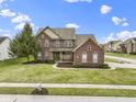 Beautiful two-story brick home with a well-manicured lawn, lush landscaping, and an inviting entrance at 10451 Meadow Lake Dr, Fishers, IN 46038