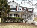 Two-story home with light-gray siding and red shutters, surrounded by a manicured lawn and mature trees at 10622 Howe Rd, Fishers, IN 46038