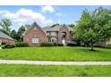 Charming brick home with a well-maintained lawn and lush green shrubbery under a bright blue sky at 12307 Pebblepointe Pass, Carmel, IN 46033