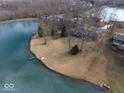 Aerial view of waterfront property with a grassy lawn and a dock on a partially frozen lake at 3752 W North Wood Lake Dr, Columbus, IN 47201