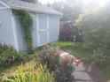 This serene backyard features a garden shed, stone pathway, mature trees, and vibrant flower beds, creating a peaceful retreat at 5757 Pebblebrooke Rd, Whitestown, IN 46075
