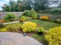 A fenced backyard oasis with lush landscaping, raised garden beds, a stone patio and mature trees for privacy at 5757 Pebblebrooke Rd, Whitestown, IN 46075