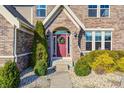 Charming brick home entrance with a red door, decorative wreath, and manicured landscaping at 5842 Oakmont Blvd, Bargersville, IN 46106