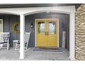 Close up of a lovely porch featuring rocking chairs, a wreath, and a cheerful yellow door at 6201 S Carroll Rd, Indianapolis, IN 46259