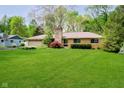 Charming ranch-style home with well-maintained lawn, stone chimney, and mature trees at 8808 Manderley Dr, Indianapolis, IN 46240