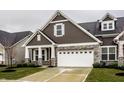 Charming home featuring brown siding, stone accents, a two-car garage and well-manicured lawn at 17099 Cole Evans Dr, Noblesville, IN 46060