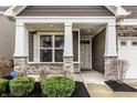 Inviting covered front porch with stone pillars, professional landscaping, and stylish front door at 17099 Cole Evans Dr, Noblesville, IN 46060