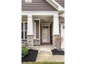 Inviting covered front porch with stone pillars, professional landscaping, and stylish front door at 17099 Cole Evans Dr, Noblesville, IN 46060