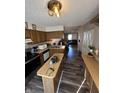 The open kitchen features wood cabinets, a kitchen island, and a view of the dining and living rooms at 1755 N Wellesley Commons, Indianapolis, IN 46219