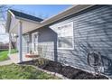 Side view of the home, features a covered porch and freshly mulched landscaping at 1755 Pinion Ct, Columbus, IN 47201