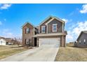 Beautiful two-story home featuring brick and siding, a two-car garage, and a well-manicured lawn on a bright, sunny day at 491 Tracewood Bnd, Greenfield, IN 46140