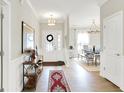 Inviting foyer with wood floors, elegant lighting, console table, and a view into the dining area at 491 Tracewood Bnd, Greenfield, IN 46140
