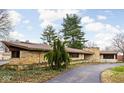 Charming ranch home featuring a stone facade, well-manicured landscaping, and a private driveway at 6461 Sunset Ln, Indianapolis, IN 46260