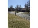 Scenic street view with a glimpse of the house, showing its proximity to a community lake and green space at 9649 Cedar Cove Ln, Indianapolis, IN 46250