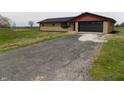 Lovely single-story brick home featuring an attached garage and a gravel driveway at 10966 W State Road 142, Quincy, IN 47456