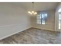 Bright dining room featuring wood floors, a modern light fixture, and a large window letting in natural light at 11144 Echo Trl, Indianapolis, IN 46236