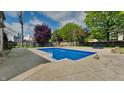 Backyard pool featuring concrete patio, wooden fence, and lush greenery providing a serene outdoor space at 11144 Echo Trl, Indianapolis, IN 46236