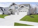 Charming two-story home featuring gray siding, stone accents, a well-manicured lawn, and a three-car garage at 19966 Chatham Green Dr, Westfield, IN 46074