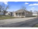 Inviting one-story house with a covered porch and light-colored exterior in a residential area with a gravel driveway at 3022 Alice Ave, Indianapolis, IN 46237