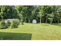 Expansive backyard surrounded by mature trees, featuring storage sheds and ample green space at 6040 W Thompson Rd, Indianapolis, IN 46221