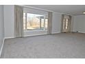 Bright living room featuring a large window with draperies and plush gray carpeting throughout at 616 Gibbs Ct, Plainfield, IN 46168