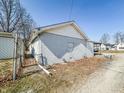 Image features backyard showing the home's exterior, gravel area, and trees at 1303 S D St, Elwood, IN 46036