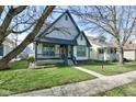 Inviting two-story home featuring a covered porch, well-maintained lawn, and mature trees at 2432 N Talbott St, Indianapolis, IN 46205