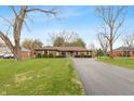 Wide view of a brick home with a long driveway, green lawn, mature trees, and a basketball hoop for outdoor recreation at 3602 N County Road 950 E, Brownsburg, IN 46112