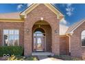 Close-up of the red brick front entrance with an arched entryway, decorative windows, and mature landscaping at 563 E Greencastle Rd, Mooresville, IN 46158